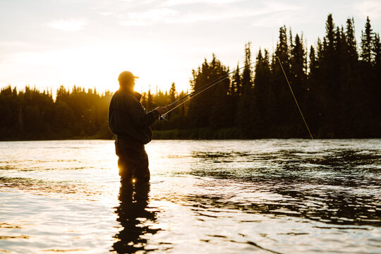 Man Fishing for Salmon During Golden Hour in Alaska River