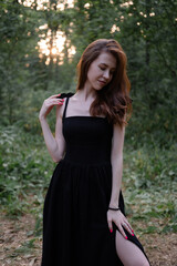 attractive young brunette woman in a black dress posing in the forest. freedom. fashion portrait