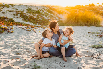 Smiling family sitting in sand at sunset