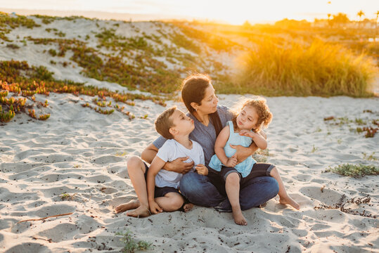 Smiling family sitting in sand at sunset