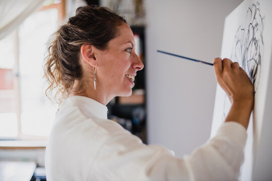 Woman paints a female portrait.