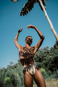 Portrait of expressive male dancer in nature with tree shadows 