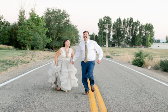 Newly Married Couple Running on Road in Wedding Attire