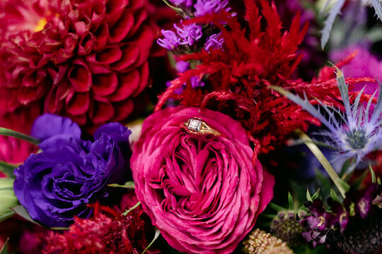 Diamond Ring Sits in Flowers of Colorful Bridal Bouquet