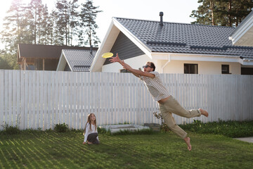 Father catching frisbee while playing with daughter