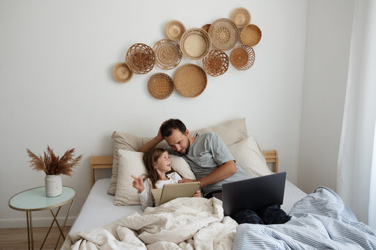 Cheerful child discussing video with dad on bed