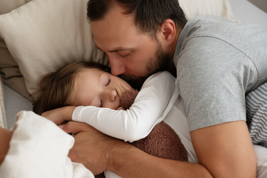 Father and daughter sleeping on bed together