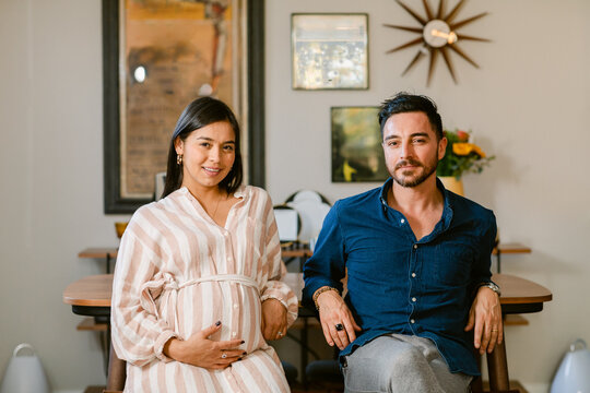 Expectant couple sitting at home portrait
