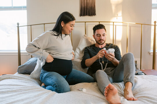 Couple in bed with device to listen to baby's heartbeat