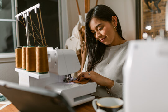 Expectant woman sewing baby clothes at home