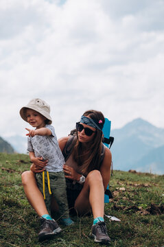 Young mom with cute son resting in nature during hiking