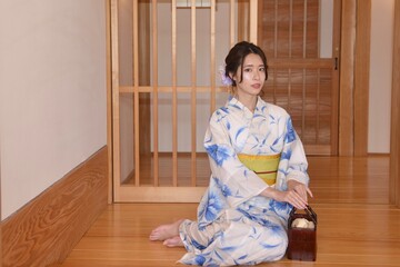 日本家屋の床の上に座りたたずむ浴衣姿の美しい女性