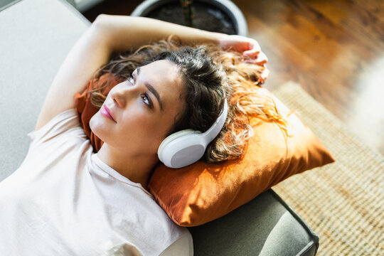 Portrait of a woman laying on sofa and enjoying music