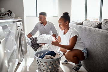 Division of labour isnt just for the workplace. Shot of a happy young couple doing laundry together...