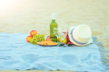 Picnic background with bag, grape and white wine on the beach by blue sea