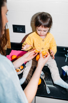 Woman and Little Girl Eating Tangerine 