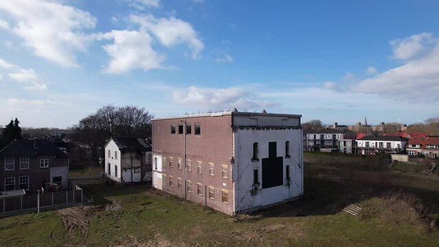Backwards aerial reveal showing surrounding of former youth prison facility, now abandoned waiting for demolition and refurbishment of the moated plot field in Zutphen, The Netherlands