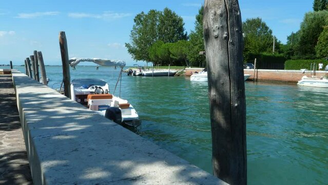 fantastic jetty  on a blue green sea  in Italy,  near Venice (canale portosecco), with little boats looked on the poles  all in all a a beautiful sunny summer day with blue sky stabile