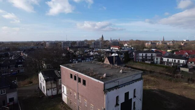 Approach of former youth prison facility, now abandoned waiting for demolition and refurbishment of the moated plot field revealing wider cityscape of Zutphen residential neighbourhoods and city