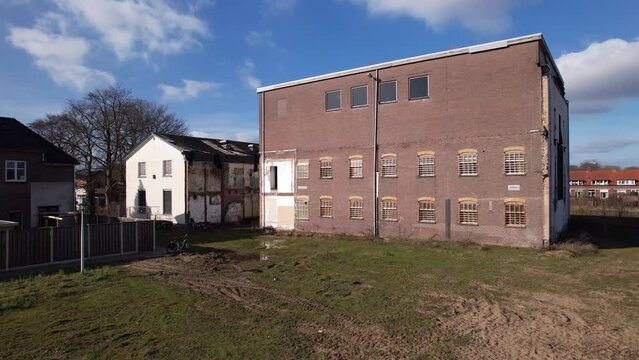 Low closeup aerial pan around former youth prison facility, now abandoned waiting for demolition and refurbishment of the moated plot field in a residential neighbourhood of Zutphen, The Netherlands