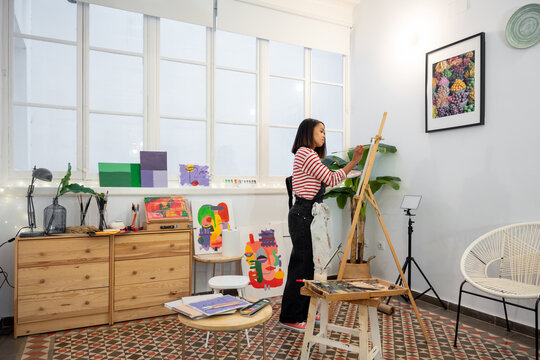 Woman painting on easel in workshop