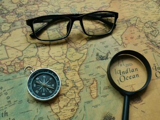 Top view compass, eye glasses and magnifier on world map. Travel and holiday concept.
