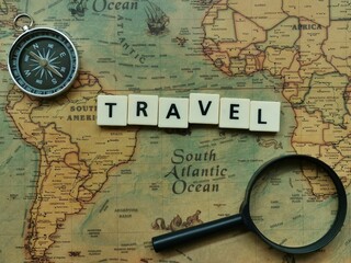 Top view text travel with compass and magnifier on world map. Travel and holiday concept.
