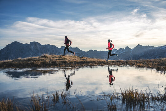 Active couple running along alpine lake
