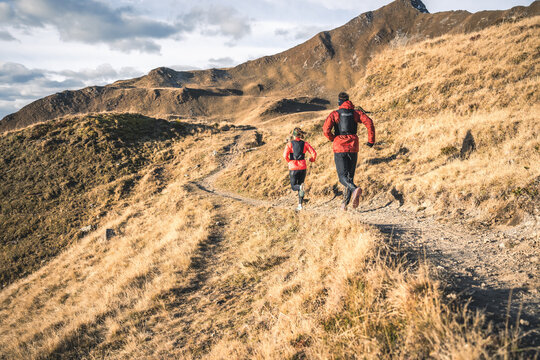 Two runners on a golden trail in the alps.
