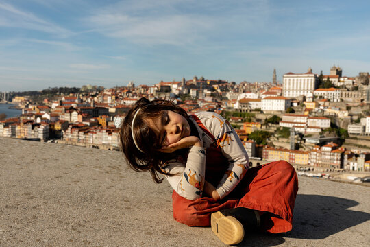 Bored girl sitting on asphalt overlooking Porto