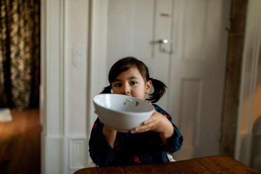 Girl showing finished cereals bowl at camera