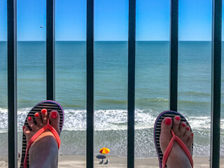 two female feet with a pedicure against the background of the ocean beachfront boardwalk Myrtle Beach South Carolina.
