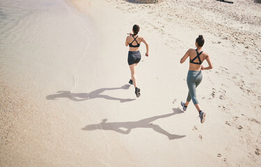 Leaving their mark on the track. High angle shot of two unrecognizable athletic young women out for a run on the beach.