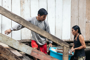 Peruvian people raising a basin to a house