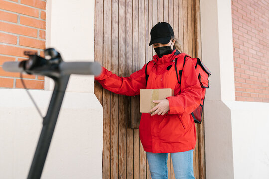 Lady reading address on parcel and knocking on door