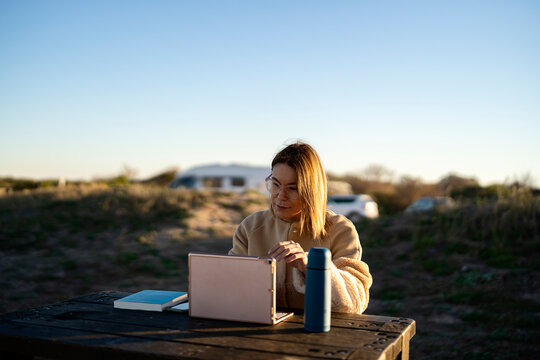 Woman surfing laptop in countryside