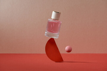 Balancing red perfume bottle on a background of geometric shapes. 