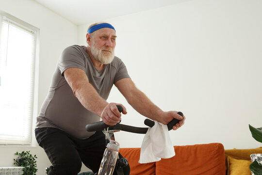 Determined senior man training on exercise bike