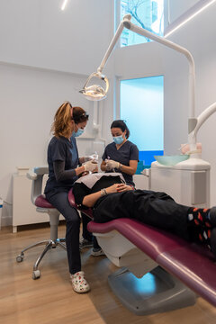 Professional dentists treating teeth of female patient