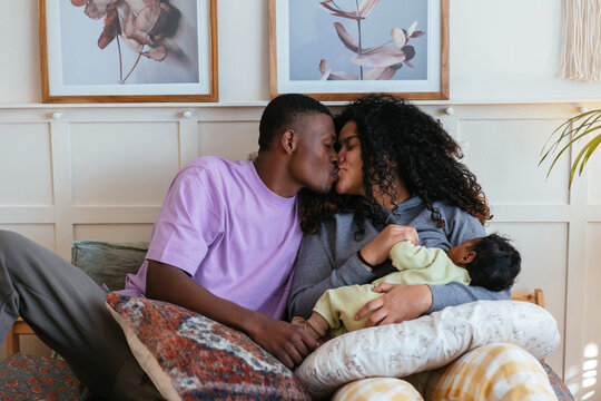 Happy black family sitting on bed at home