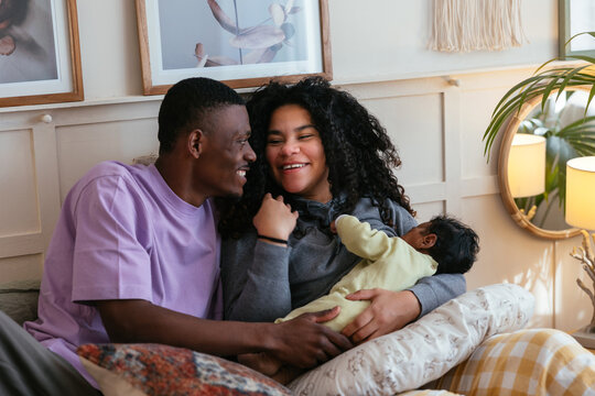 Positive black family with baby on bed