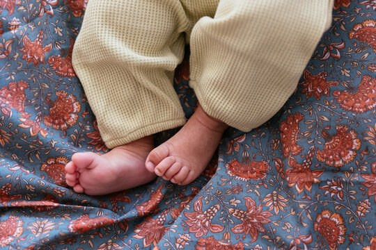 Crop infant lying on soft bed