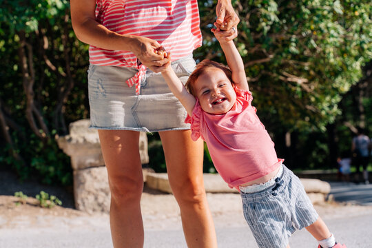 woman taking a happy baby by the arms