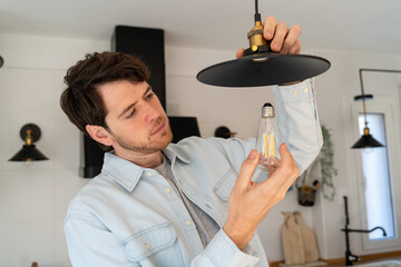 Portrait of man replacing light bulb at home
