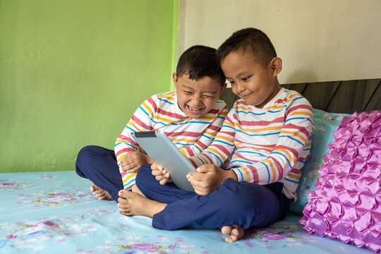 Twin Kids Watch A Video On A Tablet