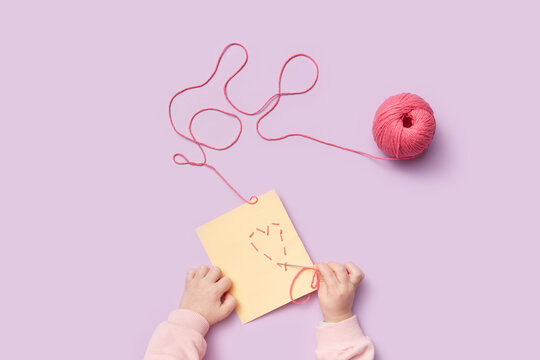 Kid making greeting card using thread and paper