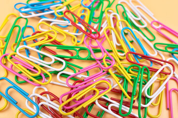 Full Frame of MultiColored Paperclips Isolated on a Cheerful Orange Beige Background