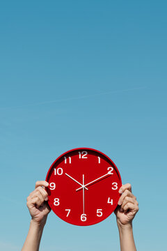 man holds a red clock, set at 10.10