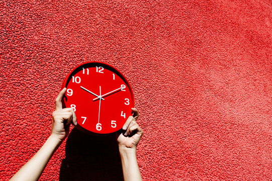 man holds a red clock