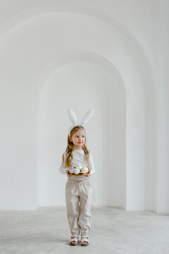 Little girl in bunny ears standing with plate of eggs
